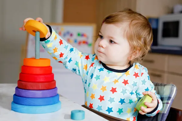 Carino bella bambina che gioca con i giocattoli educativi a casa o vivaio, in casa. Buon bambino sano divertirsi con piramide giocattolo in legno colorato arcobaleno. Apprendimento dei bambini competenze diverse. — Foto Stock