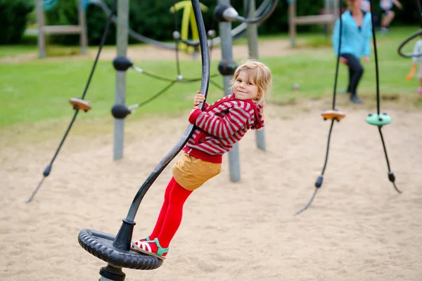 Pequena menina pré-escolar jogando no parque infantil ao ar livre. Criança feliz criança escalando e se divertindo com a atividade de verão ao ar livre. — Fotografia de Stock