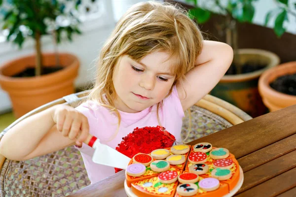 Malá roztomilá dívka hraje s dřevěnou hračkou pizzu. Mládež ve školce baví s dětmi aktivity jako, hrát si s jídlem, uvnitř. — Stock fotografie