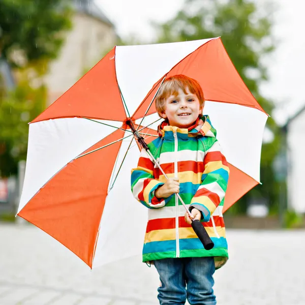 Little toddler boy playing with big umbrella on rainy day. Happy positive child running through rain and puddles. Kid with rain clothes and rubber boots. Children outdoor activity on bad weather day. — Stock Photo, Image