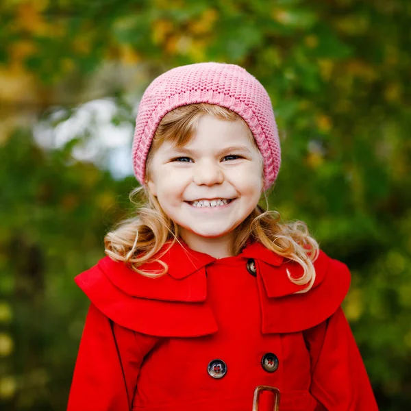 Herbstporträt eines kleinen Mädchens in rotem Mantel, das durch den herbstlichen Wald spaziert. Glückliches gesundes Baby, das mit seinen Eltern spazieren geht. Sonniger Herbsttag mit Kind. — Stockfoto