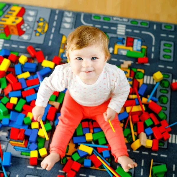 Очаровательная девочка играет с образовательными игрушками. Счастливый здоровый ребенок веселится с разноцветными деревянными блоками дома в домашней комнате. Детское обучение цветов и форм — стоковое фото