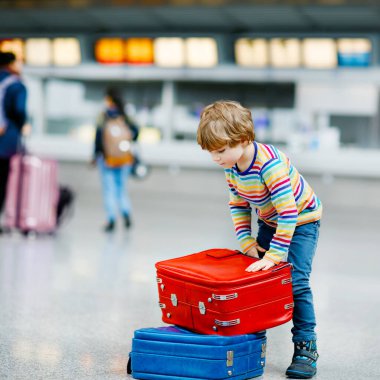 Uluslararası havaalanındaki terminalde büyük bavulları olan küçük mutlu çocuk. Okul öncesi heyecanlı çocuk uçuşu ve tatile çıkmayı bekliyor. Seyahat aile hayatı..