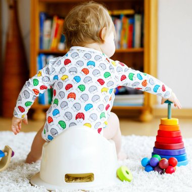 Klozetin üzerinde oturan 12 aylık küçük, şirin bebek kız çocuğunun yakın çekimi..