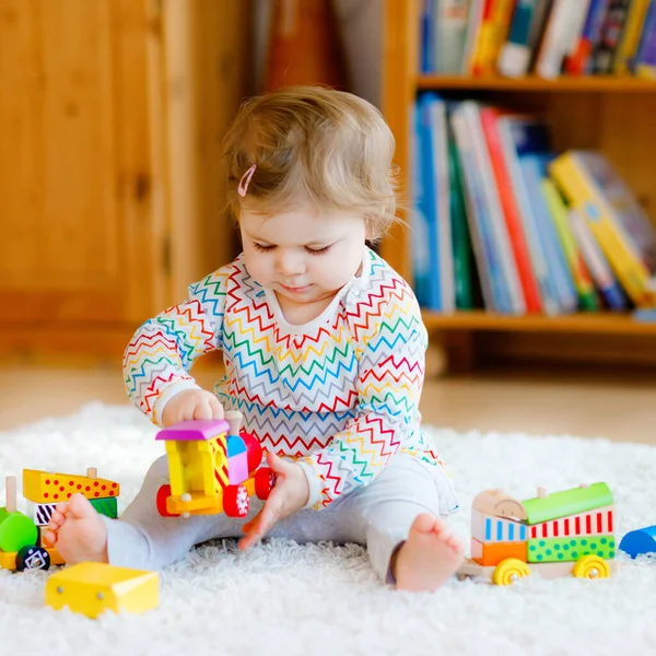 Liten flicka leker med pedagogiska träleksaker hemma eller på dagis. Småbarn med färgglada tåg. Barn som har roligt med olika leksaker. Ensam unge under koronaviruspandemisk karantän — Stockfoto