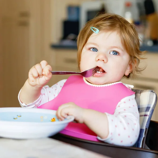 Entzückendes kleines Mädchen, das aus einem Löffel püriertem Gemüse und Püree isst. Ernährungs-, Kinder-, Ernährungs- und Personenkonzept — Stockfoto