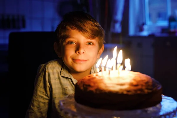 Adorable niño rubio feliz celebrando su cumpleaños. Niño soplando velas en pastel horneado casero, en el interior. Fiesta de cumpleaños para los niños de la escuela, celebración familiar —  Fotos de Stock