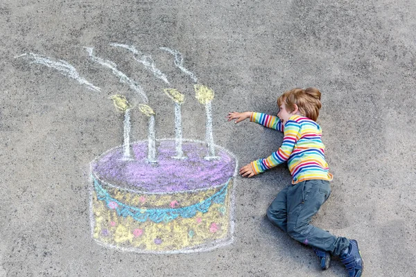Mutlu küçük çocuk renkli tebeşirle büyük bir doğum günü pastası resmiyle eğleniyor. Yazın açık havada çocuklar için yaratıcı eğlence aktivitesi. Çocuk doğum gününü kutluyor ve yere çizim yapıyor — Stok fotoğraf