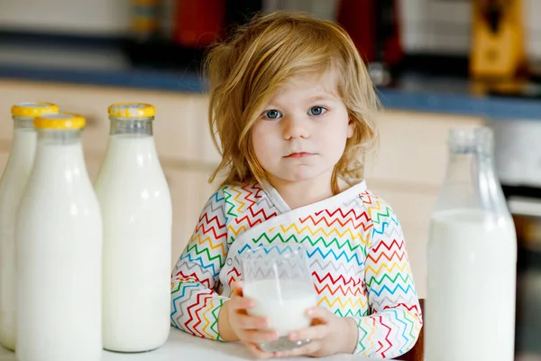 Adorabile bambina che beve latte vaccino per colazione. Carina la figlioletta con tanti biberon. Bambino sano che ha il latte come fonte di calcio sano. Bambino a casa o asilo nido al mattino. — Foto Stock