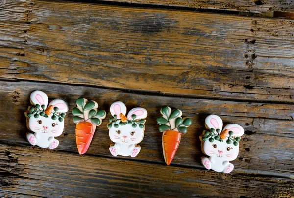 Primo piano di variazione di biscotti da zucchero pasquali diversi decorati con glassa reale. Coniglio coniglietto con carote su sfondo di legno. Delizioso regalo dolce o cartolina — Foto Stock