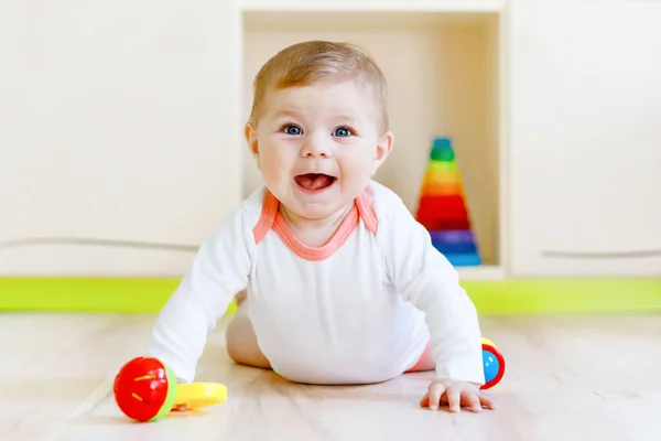 Cute happy smiling baby playing with colorful rattle toys. New born child, little girl looking at the camera and crawling. Family, new life, childhood, beginning concept. Baby learning grab. — Stock Photo, Image