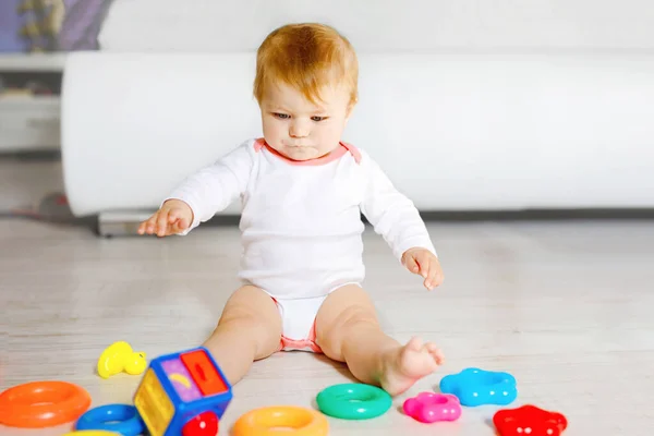 Bebek kız kreş eğitici oyuncaklar ile oynama. Mutlu sağlıklı çocuk evde renkli yumuşak oyuncaklar ile eğleniyor. Evlat plastik piramit inşa etmeye ve harflerle bloğu kullanma — Stok fotoğraf