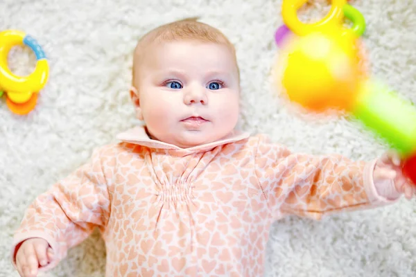 Leuke schattige pasgeboren baby spelen met kleurrijke rammelaar speelgoed op witte achtergrond. Nieuw geboren kindje, kleine meid op zoek hand van moeder of vader. Familie, jeugd, nieuw leven en begin concept — Stockfoto