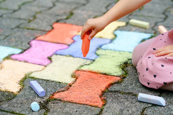 Liten förskola flicka målning med färgglada kritor på marken på bakgården. Positivt glad barn rita och skapa bilder. Kreativ friluftsaktivitet på sommaren. — Stockfoto