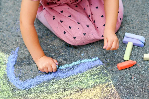Kleine Vorschulmädchen malen Regenbogen mit bunten Kreiden auf dem Boden im Hinterhof. Positiv glückliches Kleinkind, das zeichnet und Bilder schafft. Kreative Aktivitäten im Sommer. — Stockfoto