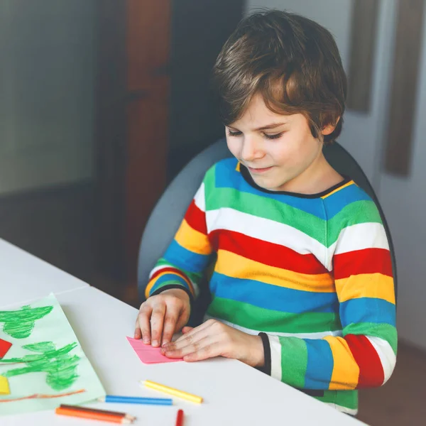 Kleine jongen maken papier origami tulp bloemen voor een ansichtkaart voor moeders dag of verjaardag. Schattig kind van de lagere school die handwerk doet — Stockfoto