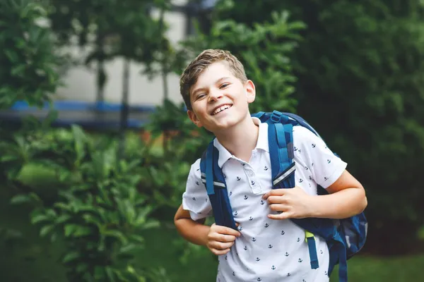 Lycklig liten pojke med väska, gående. Skolbarn på väg till mellanstadiet eller gymnasiet. Spännande barn utomhus på skolgården. Tillbaka till skolan. — Stockfoto
