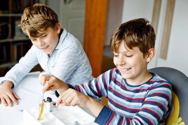 Dos chicos haciendo experimentos físicos eléctricos como tarea en casa. Los niños estudian electricidad. Educación. Mejores amigos, hermanos aprendiendo física. —  Fotos de Stock