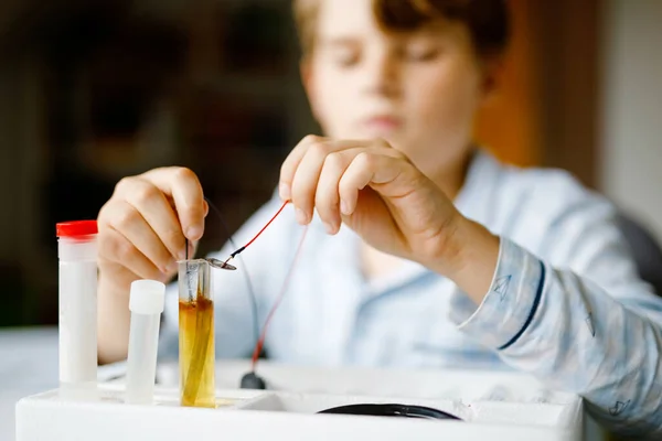 Szoros kép egy kisfiúról, aki elektromos fizikai kísérleteket végez házi feladatként otthon. A gyerek elektromosságot tanul. Oktatás. A gyerekek fizikát tanulnak. — Stock Fotó