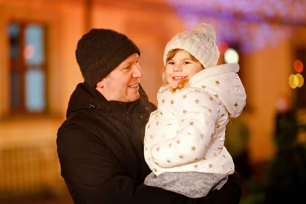 Almanya 'da Noel pazarında babasının omzunda oturan küçük bir anaokulu kızı. Alman şenlik şehrinin sokaklarında yürüyen mutlu çocuk ve adam. Aile, kaynaşma, aşk. Aile Xmas zamanı. — Stok fotoğraf