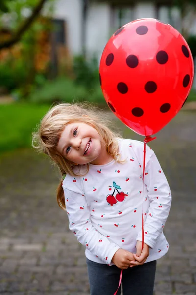 Linda niña preescolar feliz jugando con el globo mariquita al aire libre. Pequeño niño celebrando cumpleaños. — Foto de Stock