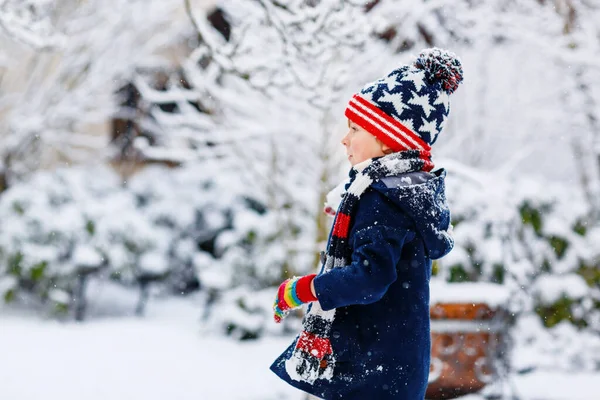 Vtipné malý kluk chlapec v barevných šatech hraní venku během silného sněžení — Stock fotografie