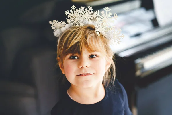 Menina pré-escolar bonito com coroa floco de neve olhando para a câmera. Criança feliz adorável celebrando Natal e férias de inverno. — Fotografia de Stock