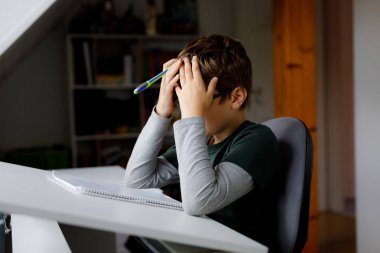 Karantina zamanında Corona salgınından ev ödevi yapan çalışkan, üzgün okul çocuğu. Coronavirus covid zamanında evde eğitim gören yorgun çocuk, okullar kapalı..