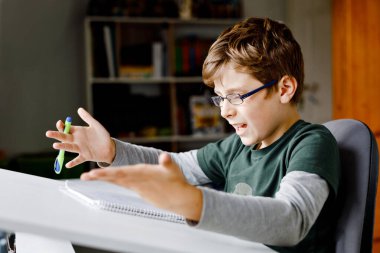 Karantina zamanında Corona salgınından ev ödevi yapan çalışkan, üzgün okul çocuğu. Coronavirus covid zamanında evde eğitim gören yorgun çocuk, okullar kapalı..