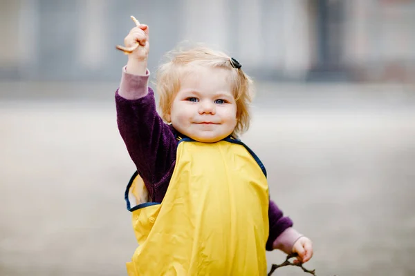 Menina adorável bonito criança brincando ao ar livre no dia da primavera. Criança usando calças amarelas de chuva de lama. Retrato de menina feliz. — Fotografia de Stock