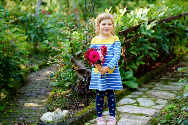 Klein kleuter meisje met enorme boeket bloeiende rode en roze dahlia bloemen. Gelukkig kind met bloemen in de hand. Peuter met pioenrozen voor moeder of verjaardag. Tuinkinderen. — Stockfoto