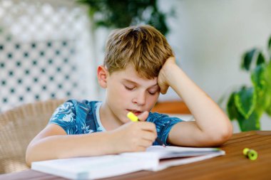 Çalışkan, mutlu okul çocuğu Corona salgınından dolayı karantina zamanında ödev yapıyor. Kalemle yazan sağlıklı bir çocuk, evde kalıyor. Evde eğitim kavramı