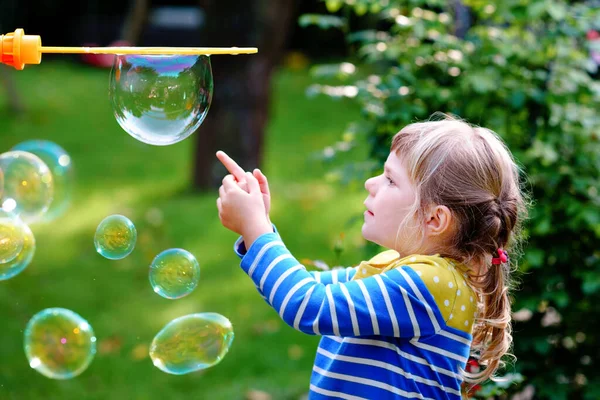 Feliz niña rubia preescolar divirtiéndose con el soplador de jabón burbuja. Lindo niño jugando en el soleado día de verano. Chico sano divertido activo feliz. Actividad para niños. —  Fotos de Stock