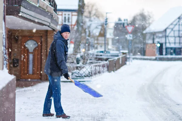 在冬天下雪的时候，拿着铲子的人清扫人行道。欧洲的冬季。穿着温暖冬衣的年轻人。德国的雪和天气混乱。暴风雪和大雪。Schneechaos案 — 图库照片