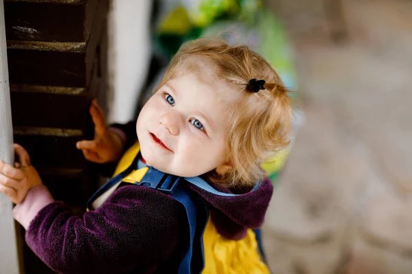 Linda adorable niña jugando al aire libre en el día de primavera. Bebé niño con pantalones de charco de lluvia de barro amarillo. Retrato de chica feliz. — Foto de Stock