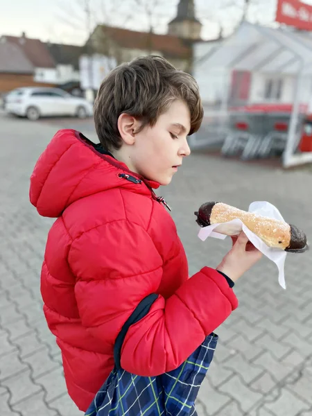 Мальчик ест сладкий пирог по-немецки Kreppel или rugelach sufganiyot. Ребенок с тортом, религиозная еда для карнавала Fasching в Германии или еврейского фестиваля Ханукки — стоковое фото