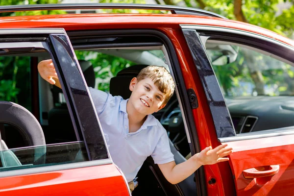Glückliches Kind, Schulkind, das im Auto sitzt, bevor es mit den Eltern in die Sommerferien geht. Glückliches Kind durch Autoscheibe auf Reise, Familie Roadtrip — Stockfoto