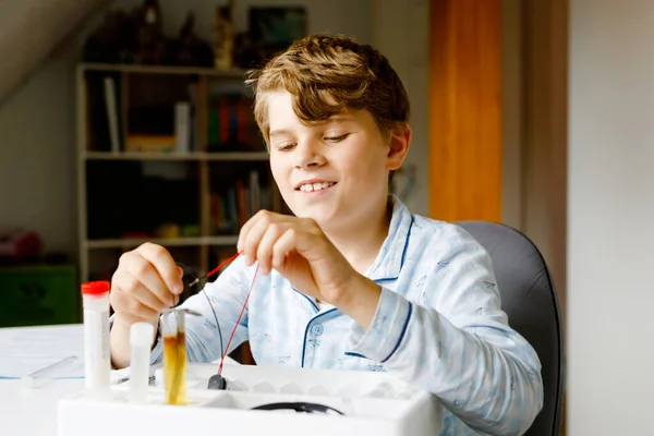 Kaméleon fiú elektromos fizikai kísérleteket végez házi feladatként otthon. A gyerek elektromosságot tanul. Oktatás. A gyerekek fizikát tanulnak. — Stock Fotó