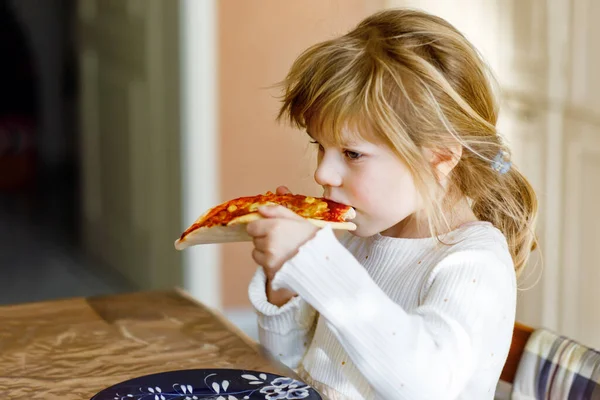 Menina da criança adorável comer pizza italiana com legumes e queijos. Criança feliz comendo refeição saudável cozida fresca com tomate, milho e legumes em casa, dentro de casa. — Fotografia de Stock