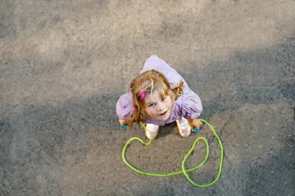 Liten förskola flicka hoppa och träna med hoppa rep. Vy ovanifrån på söta glada aktiva barn. Sommarsport och aktivitet för fysisk och psykisk kondition hos barn. — Stockfoto