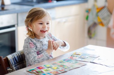 Heyecanlı, gülümseyen küçük kız iskambil oynuyor. Mutlu sağlıklı çocuk hafızasını eğitiyor, düşünüyor. Çocuk için evde yaratıcı bir eğlence ve eğitim. Evde aile aktivitesi.