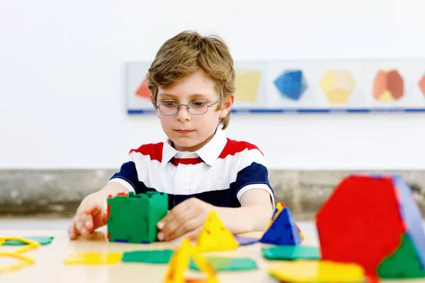 Šťastný chlapec s brýlemi baví s budováním a vytvářením geometrických figurek, učení matematiky a geometrie — Stock fotografie
