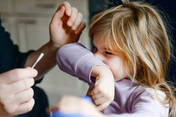 Ojciec robiący domowy wirus korony nosowej smakuje małej dziewczynce, przedszkolaku. Córka i tata zrobić covid domu test antygenu z wacikiem. — Zdjęcie stockowe