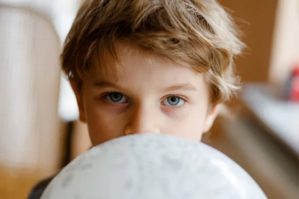 Piccolo bambino biondo in età prescolare con pallone aerostatico che gioca al chiuso a casa o all'asilo. Bambino divertente divertirsi da solo. Infanzia felice, asilo nido, scuola — Foto Stock