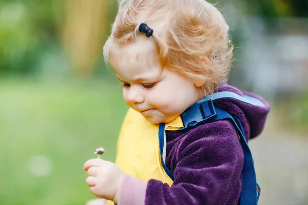 Roztomilé roztomilé batole dívka hraje venku na jaře. Dítě má na sobě žluté kalhot z kalhot. Portrét šťastné dívky. — Stock fotografie