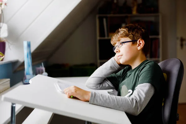 Kid boy with glasses learns at home for school. Preteen child making homework. Home schooling and distance learning concept. — Fotografia de Stock