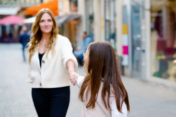 Junge Mutter und schulpflichtiges Mädchen spazieren durch die Stadt. Glückliche Familie, Frau und Tochter mit Brille genießen die gemeinsame Zeit. Liebe und Unterstützung der Eltern. Das Glück von Mutter und Kind. — Stockfoto