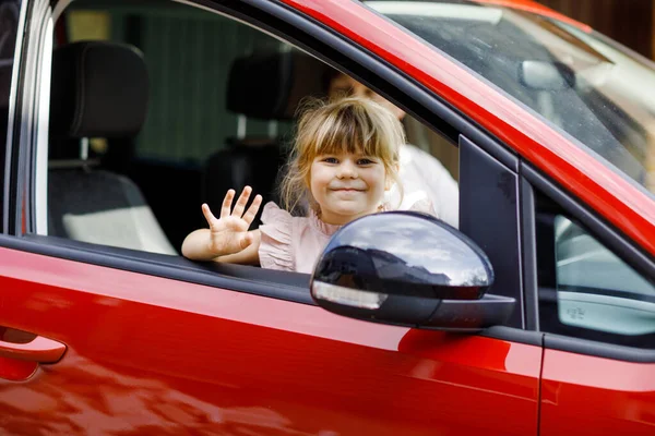 Enfant heureux, petite fille préscolaire assise en voiture avant de partir pour des vacances d'été avec les parents. Joyeux enfant par fenêtre de voiture en voyage, voyage en famille — Photo