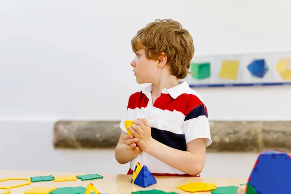 Menino feliz se divertindo com a construção e criação de figuras geométricas, aprendendo matemática e geometria — Fotografia de Stock