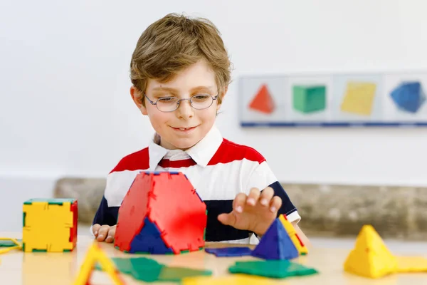 Niño feliz con gafas que se divierten con la construcción y la creación de figuras geométricas, el aprendizaje de las matemáticas y la geometría — Foto de Stock
